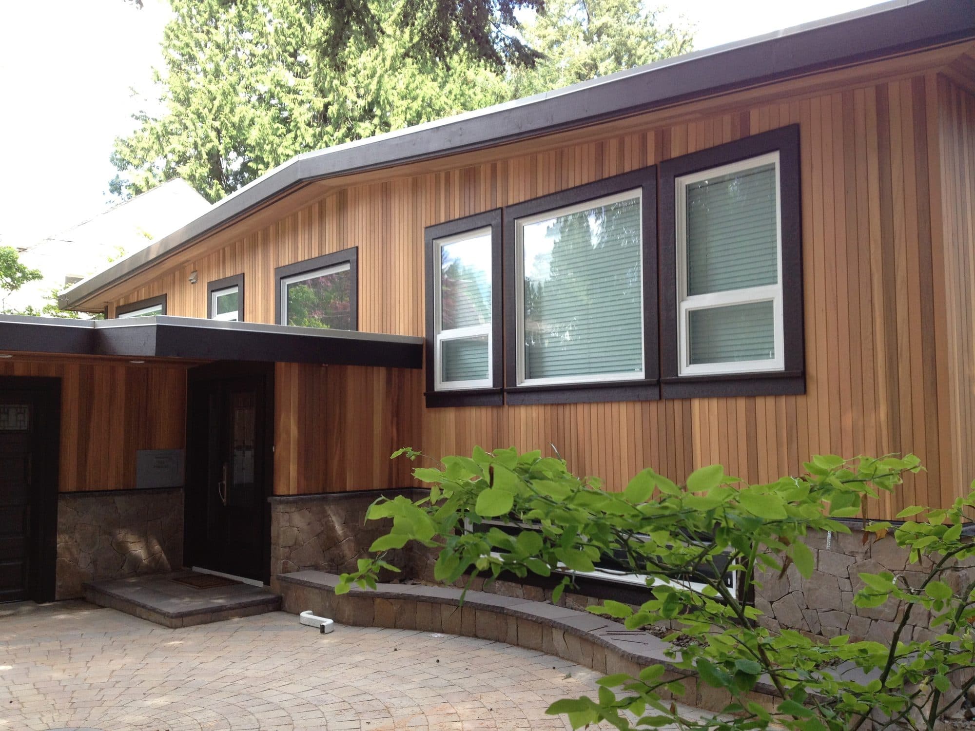 Finished home with clear cedar siding, dark trim and stone base by Grain Construction